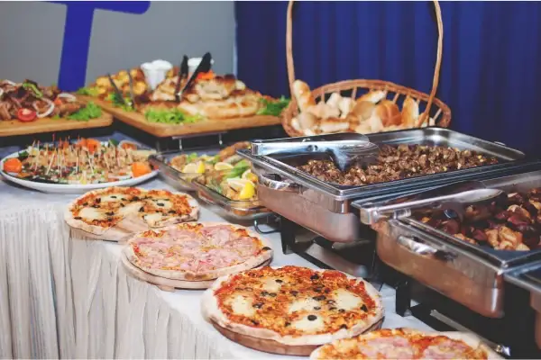 Selection of buffet foods including pizzas, meats and bread to show the questions to ask when choosing a food catering service.
