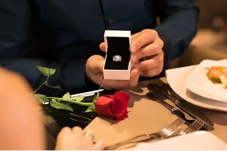 Man proposing at a dinner table with a rose on it