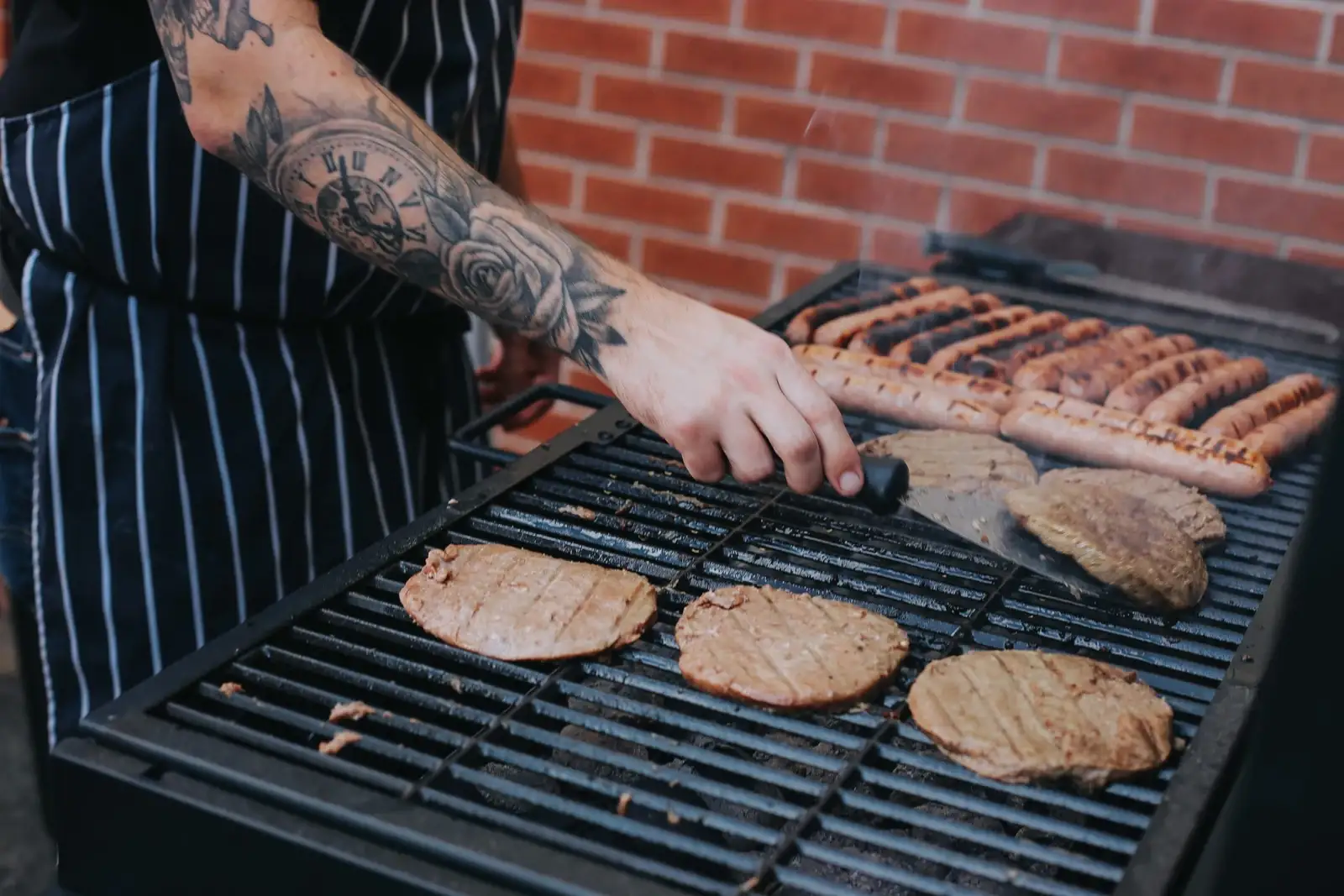 A chef preparing meats on a barbecue on the hottest day of the year.