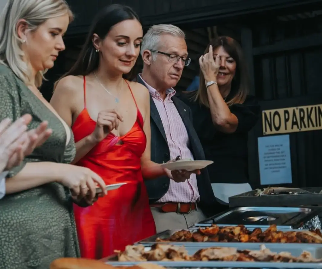 A woman wearing a red dress with her family creates a memorable graduation party with a catering experience that's delicious.