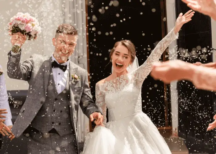 A newly wedded couple leaving their wedding ceremony outside a church to go to their reception with pizza catering.