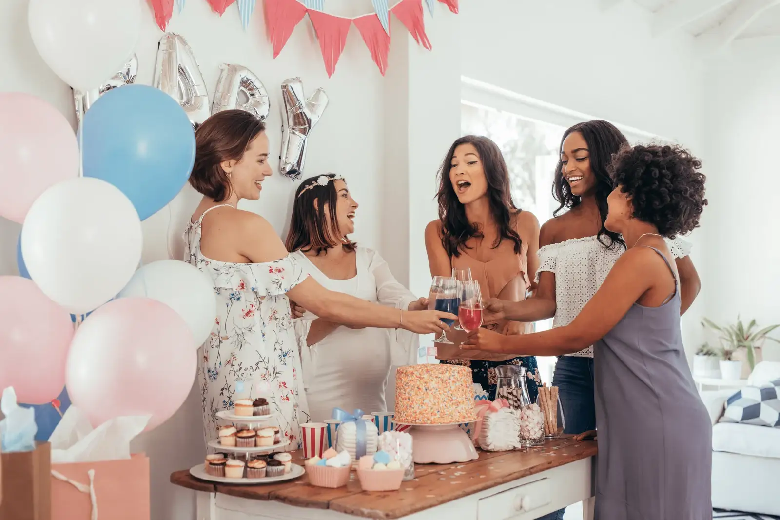 A pregnant woman and her friends having a baby shower celebration to show why you should have a baby shower in the summer