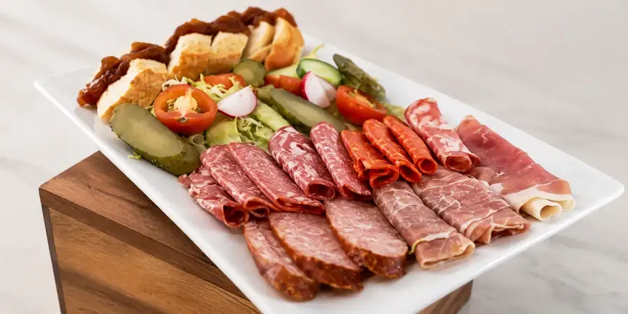 Board of dried cured meats with gherkins, pickles and crusty bread
