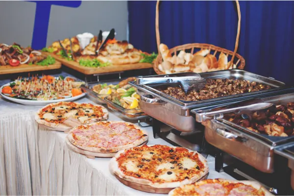 Selection of buffet foods including pizzas, meats and bread to show the questions to ask when choosing a food catering service.