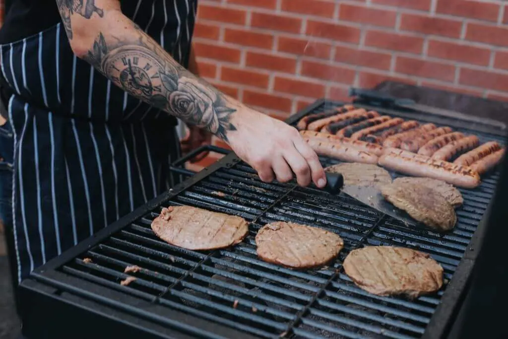 A chef preparing meats on a barbecue on the hottest day of the year.