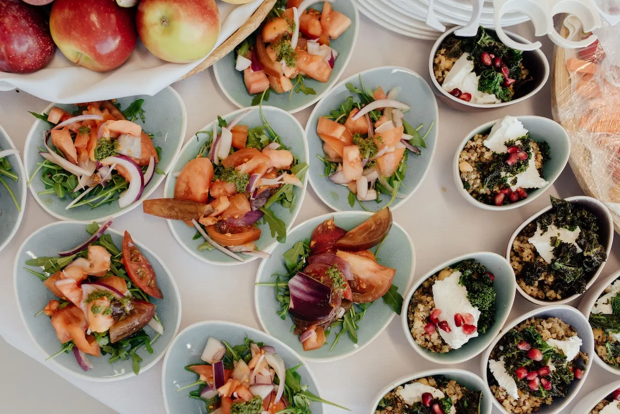 Several salads and fruit displayed on a table at an office party after their company hired Sadlergates for their catering.