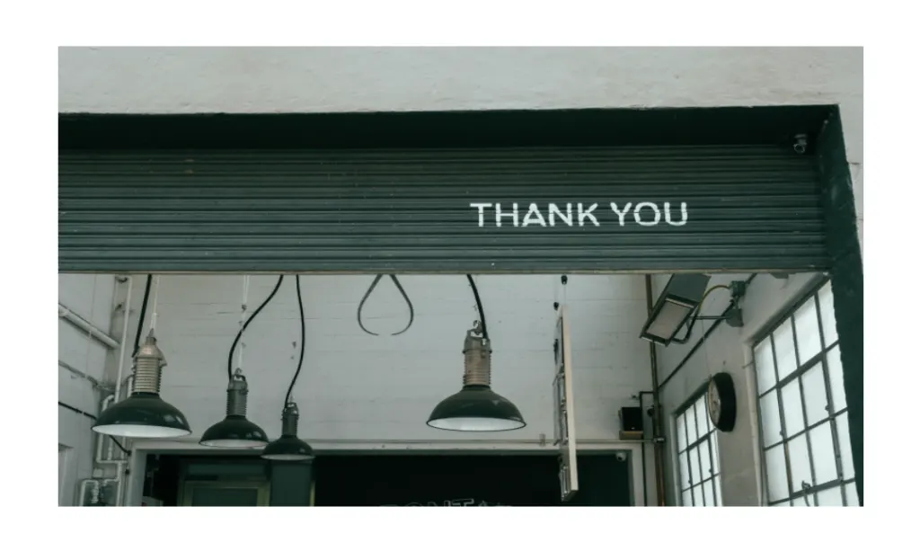 THANK YOU painted in white on a dark roller shutter above an industrial doorway