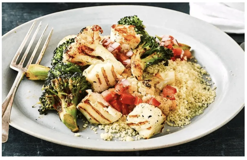 A plate of grilled halloumi with charred broccoli, couscous and chopped tomato