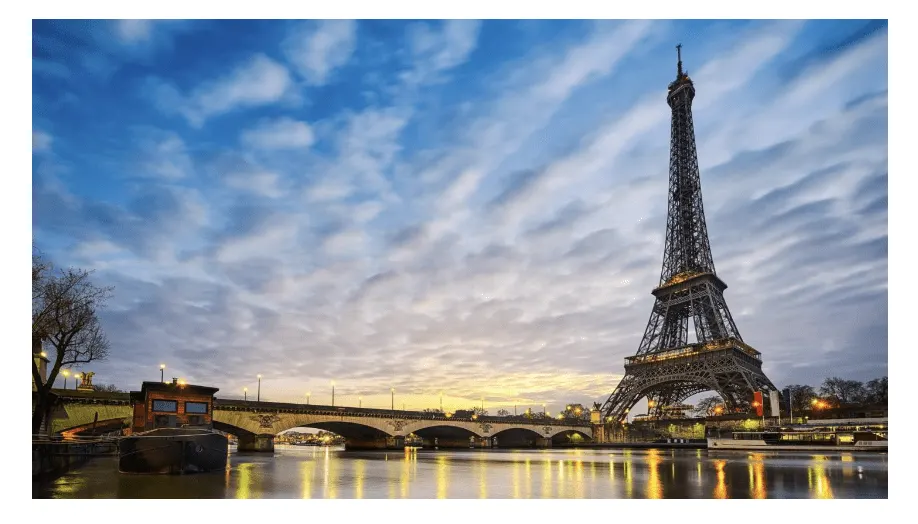 The Eiffel Tower and the Seine at dusk, with lights reflected in the water