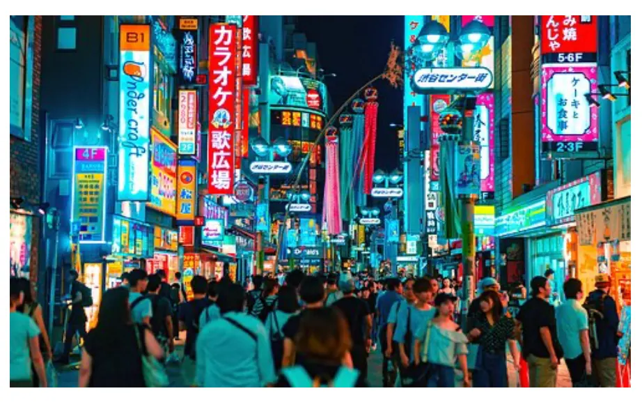 A crowded Tokyo street at night, lined with neon signs